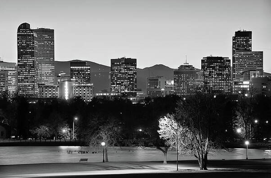 Black and white city skyline at night with illuminated buildings.