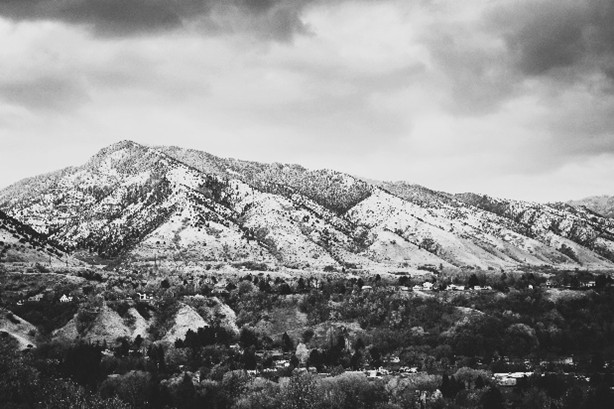 Black and white photo of a rugged mountain range under a cloudy sky.
