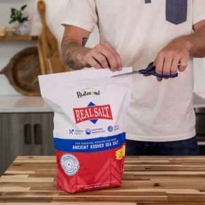 Person cutting a bag of sugar with scissors.