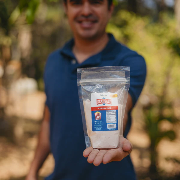 Person holding a bag of white powder product outdoors.